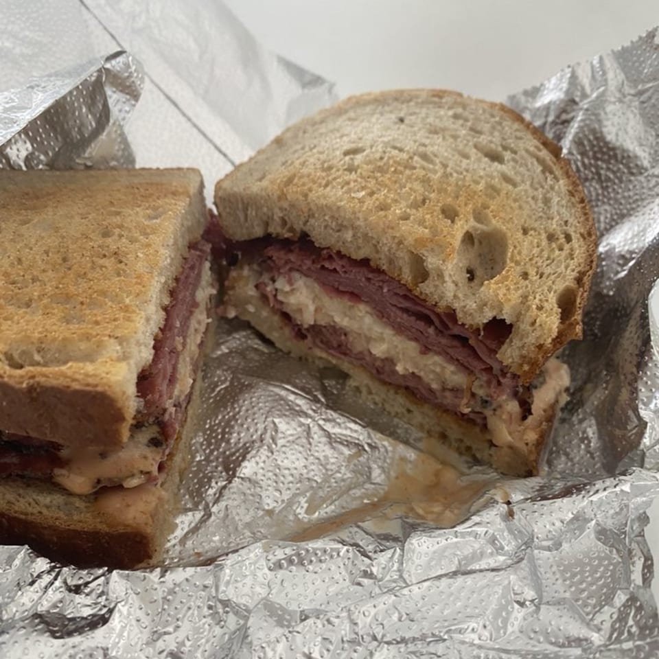 A Bing's Beach House Deli sandwich, cut in half, with pastrami, coleslaw, and Russian dressing.