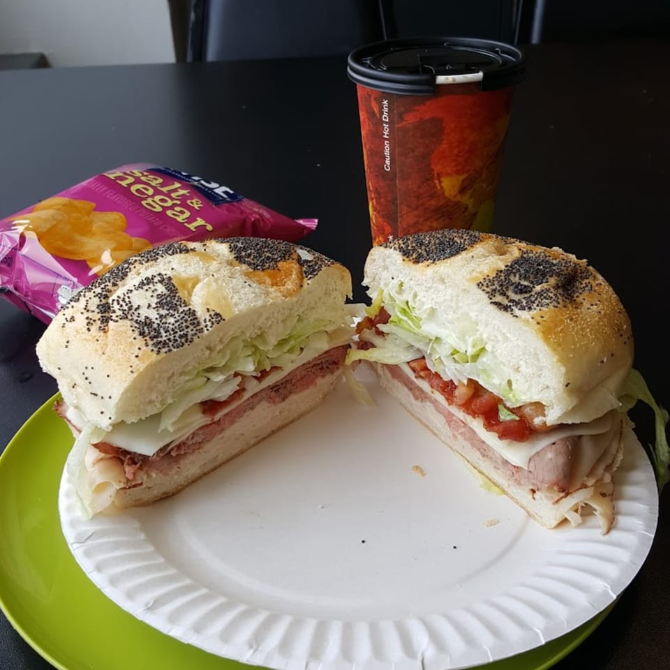 A Bing's Beach House Deli sandwich, cut in half, with chips and a hot drink.